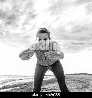 Refreshing wild sea side workout. young active woman in sportswear on the seashore stretching Stock Photo