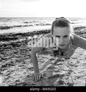 Refreshing wild sea side workout. active fitness woman in sportswear on the beach doing pushups Stock Photo