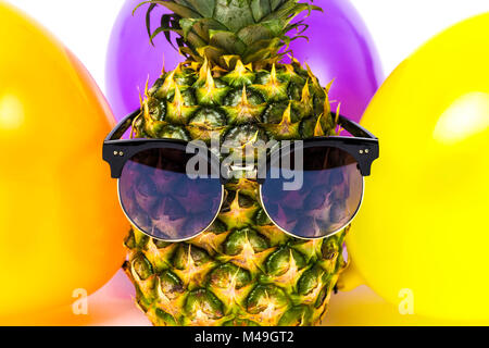 close-up image pineapple in glasses among colorful balloons, isolated on white background, concept of birthday Stock Photo