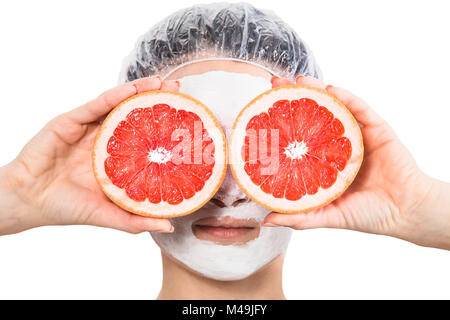 Girl with fruit mask on face holds red grapefruits at eyes level isolated on white background Stock Photo