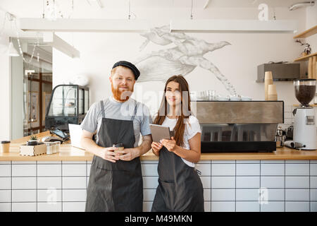 Coffee Business Concept - happy young bartender baristas ready to give service at modern coffee shop. Stock Photo