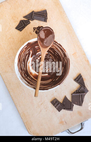 Melted dark chocolate and wooden spoon on a ceramic mixing bowl Stock Photo