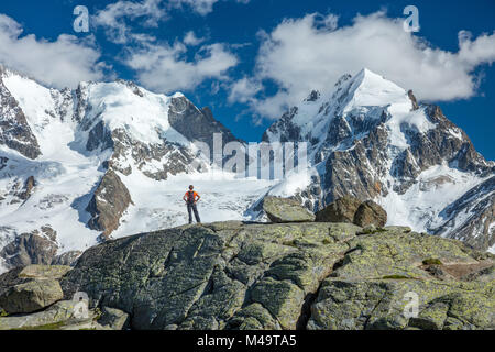 Hiker beneath Piz Bernina and Piz Rosbeg, Fuorcla Surlej, Berniner Alps, Graubunden, Switzerland. Stock Photo