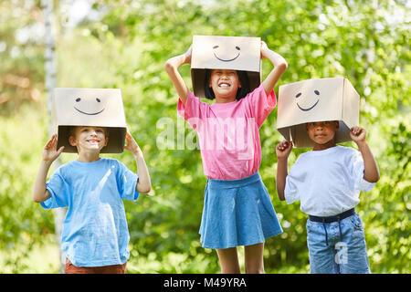 Creative kids play with funny cardboard boxes on their heads in nature Stock Photo