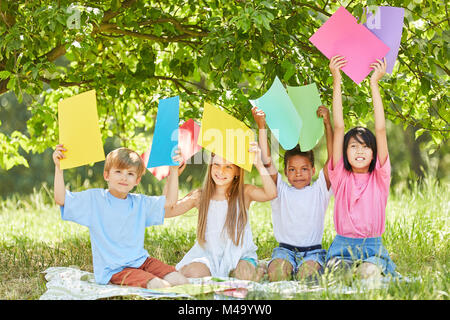 Children of creative craft group hold colorful cartons high in the park Stock Photo