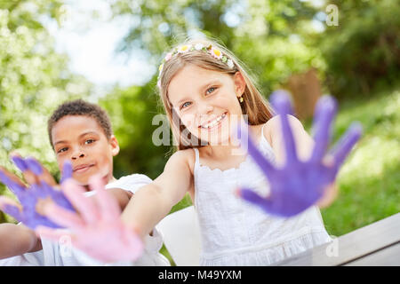 Children play and paint with finger paints on birthday party in the garden Stock Photo