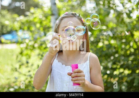 Girl blows soap bubbles in the summer as a sign of transience Stock Photo