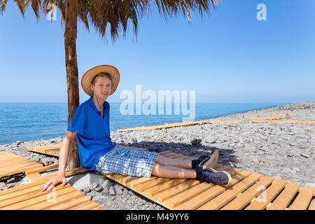 Dutch boy sitting under parasol on portuguese beach Stock Photo