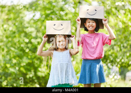 Two girls play with funny painted cardboard boxes in the summer in nature Stock Photo