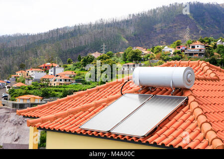 Water boiler with solar panels on roof of house Stock Photo