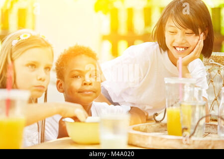 Happy kids eating breakfast cereal together at summer camp Stock Photo