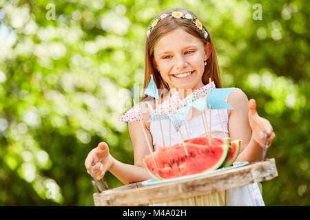 Smiling girl as a birthday girl is serving fresh watermelons Stock Photo