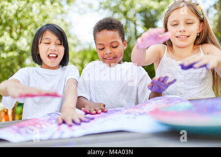 Creative kids as friends play with finger paints on kids birthday Stock Photo