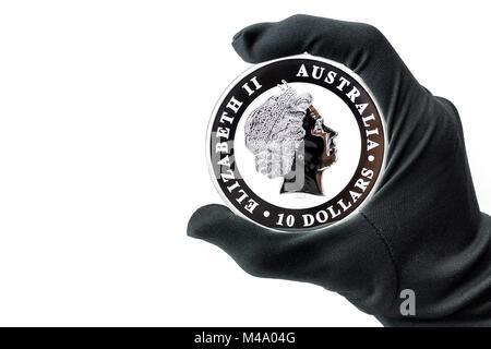 Hand in black glove holding large silver dollars coin Stock Photo