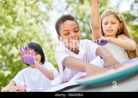 African boy plays and paints with finger paints with his friends Stock Photo