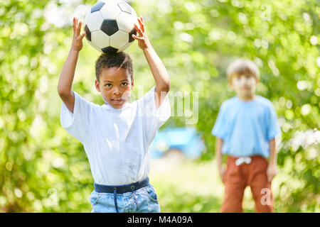 African boy is balancing a football on the head in nature Stock Photo