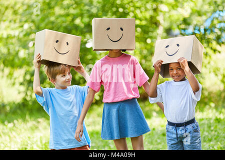 Three children play with fantasy with funny painted cardboard boxes in the garden Stock Photo