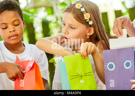 Girl as a birthday girl unpacks a present at the birthday party Stock Photo