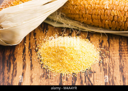 Corn groats and seeds, corncobs on wooden rustic table Stock Photo