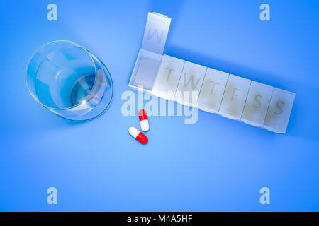 reminder box for pills and a glass of water Stock Photo