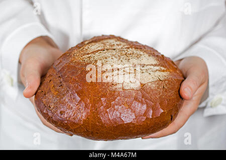 Baker holding fresh bread in the hands of Stock Photo