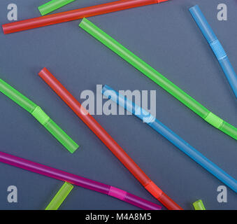 plastic multicolored straws for cocktail are scattered on a black background Stock Photo