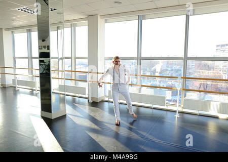 Young blonde dancer enjoys winning in white suit and makes warm  Stock Photo