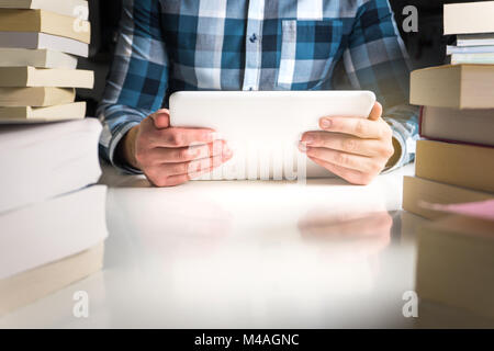 Man holding electronic book reader. Student reading book with tablet and smart mobile device in library or home. Stock Photo