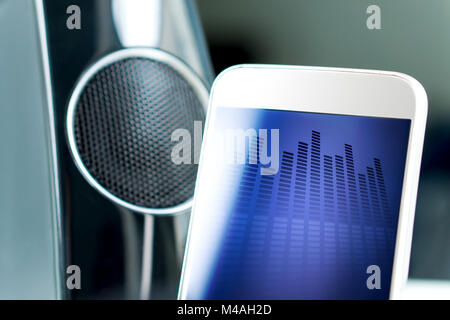 Music streaming with modern portable and wireless smart speaker. Mobile sound application on smartphone screen. Stock Photo