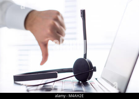 Unhappy help desk, support hotline or call center person showing thumbs down. Tele marketing professional having horrible day, not satisfied. Stock Photo