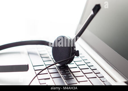 Help desk, customer service, support hotline or call center concept. Close up of headset on laptop keyboard. Video call conference or telemarketing. Stock Photo