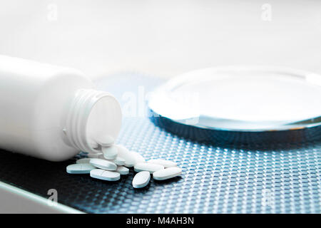 Weight loss pills on a scale. Diet medicine spilled out from bottle. Stock Photo