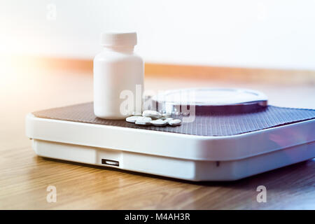 Diet pills on a scale. Weight loss medicine spilled out from bottle. Stock Photo