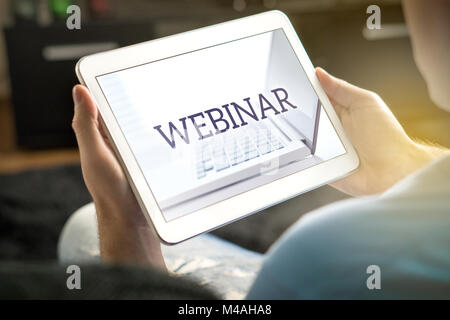 Webinar on tablet screen. Man holding smart mobile device and participating in a web seminar. Stock Photo