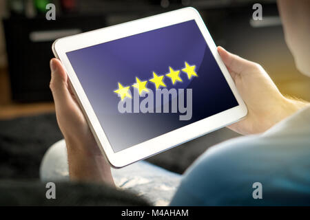 Five star rating and review from satisfied and happy customer and reviewer. Man holding tablet with an imaginary criticism application, social media. Stock Photo