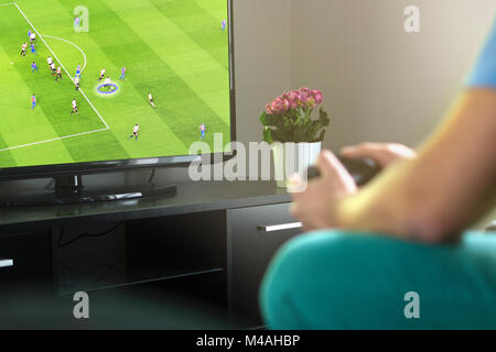Man playing imaginary soccer or football console game on tv at home. Holding gamepad in hand. Fun freetime activity. Stock Photo