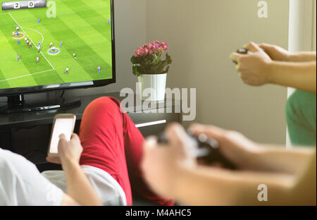 Group of friends hanging out and playing imaginary soccer or football video game with console and tv. Guys night, party and weekend concept. Stock Photo