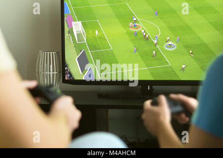 Two guys playing imaginary multiplayer soccer or football video game with console and tv. Guys night, party and weekend concept. Stock Photo