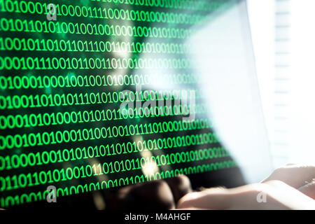 Hacker writing code with laptop computer. Binary numbers, zero and one on monitor screen. Cyber security threat, attack and online crime concept. Stock Photo