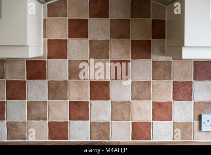 Section of tiled kitchen wall, above a hob with parts of cabinets on either side. Stock Photo