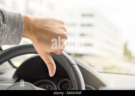 Sad driver showing thumbs up in car. Dissatisfied man. Bad customer service by repair shop. Vehicle broken. Failed driving school test or inspection.  Stock Photo