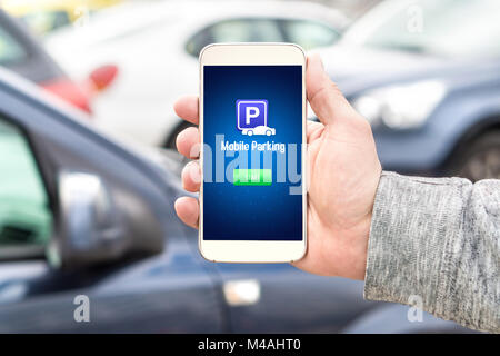 Mobile parking app on smartphone screen facing camera. Man holding smart phone with car park application in hand. Internet payment online. Stock Photo