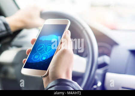 Internet of things (IOT) mobile app in smart phone for modern car. Hand holding smartphone with futuristic ADAS system. Stock Photo