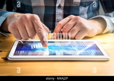 Business man using tablet and looking at financial graphs or planning economic investment strategy. Modern smart mobile device on table with data. Stock Photo