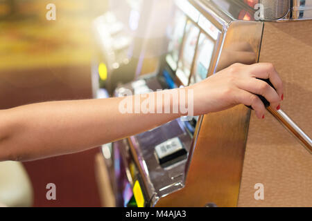 Woman pulling the handle on a slot machine in a casino. Gambling, luck, taking risk and winning jackpot concept. Gambler playing in Las Vegas. Stock Photo