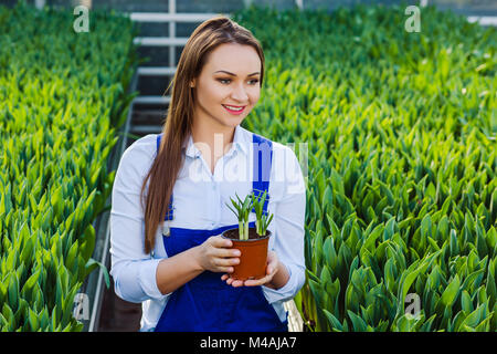 Woman gardener standing in the garden center, with a potted plant in her hands Stock Photo