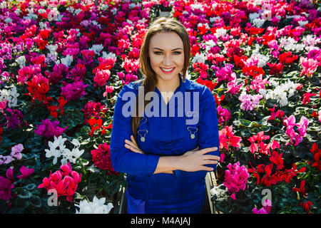 Portrait of a gardener florist, standing in a shopping center, looking at camera and smiling. Grow flowers in the greenhouse. Stock Photo