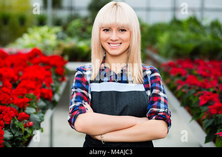 Young smiling woman florist standing in a greenhouse Stock Photo
