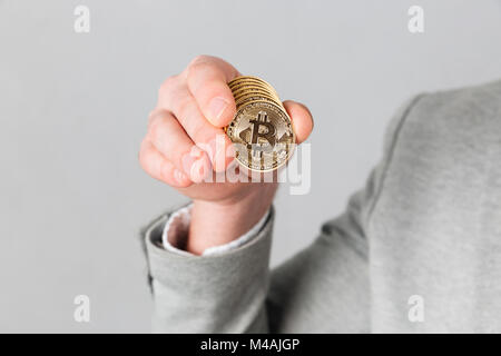 Close up of male hand showing golden bitcoin isolated over gray background Stock Photo
