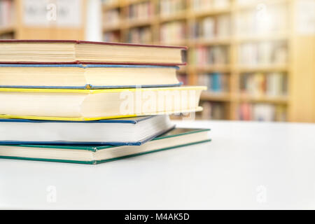 Stack and pile of books on table in public or school library. Education, studying and literature service concept with negative copy space. Stock Photo